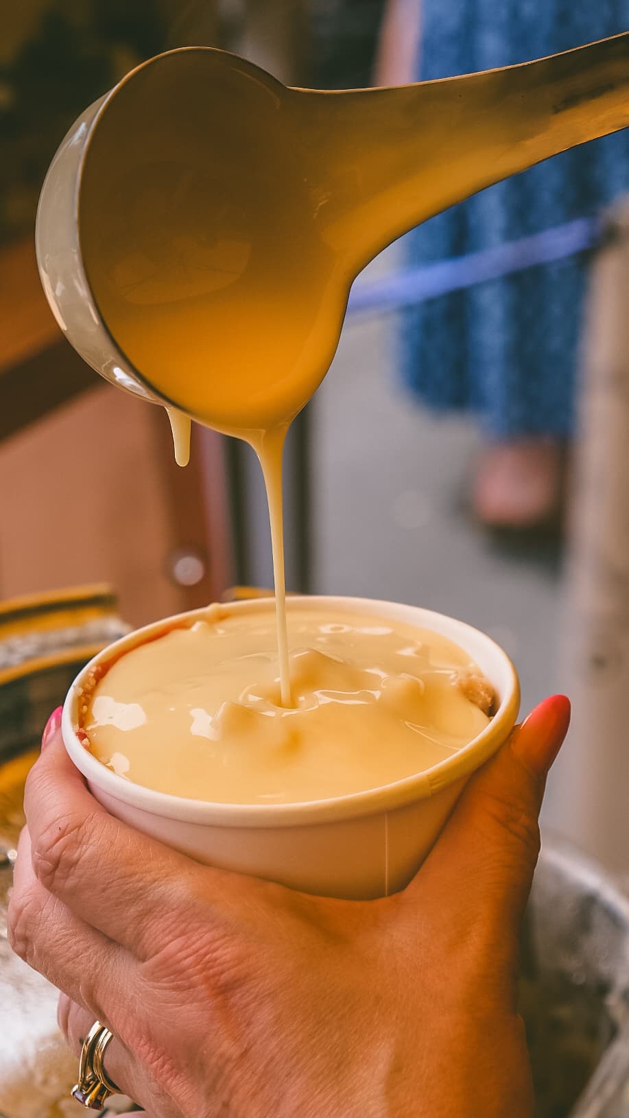 Custard being poured over a fresh, hot crumble